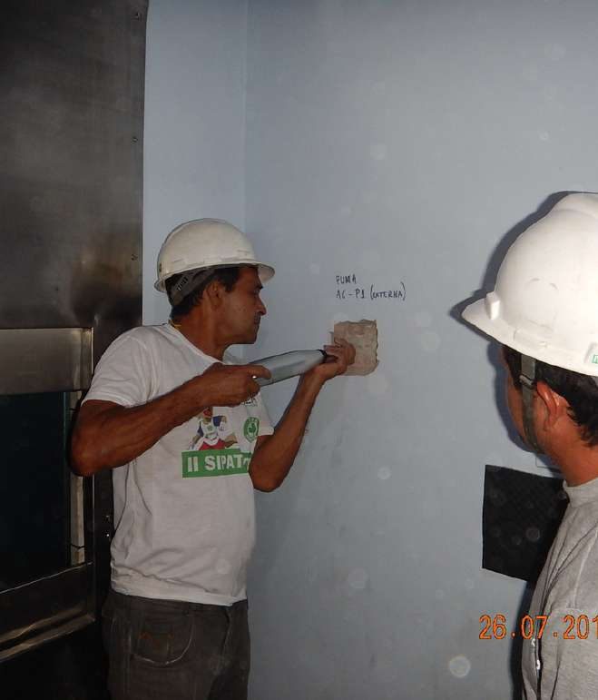 Engenheiros de capacete inspecionando uma parede com marcações técnicas